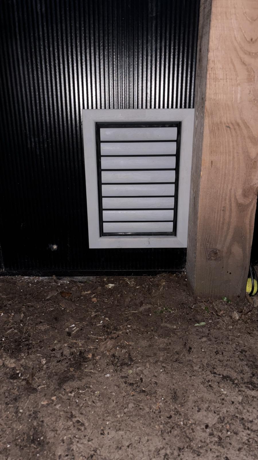 Wit gelakt luik ingebouwd in een zwarte schuurwand